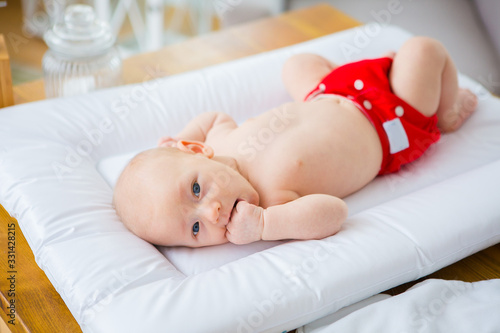 Mother changing reusable diaper or nappy. Reusable diaper and infant. Baby with eco diaper. 