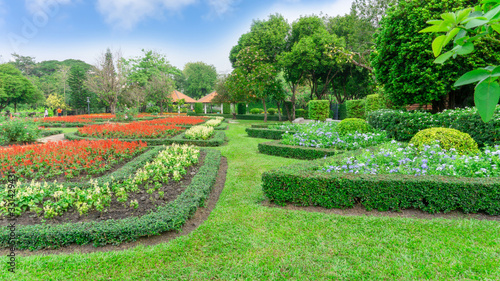 Gardens with geometric shape of bush, decoration flowering plant blooming, green leaf of Philippine tea plant, greenery trees, gazebo on background in a good care landscapes of a public park