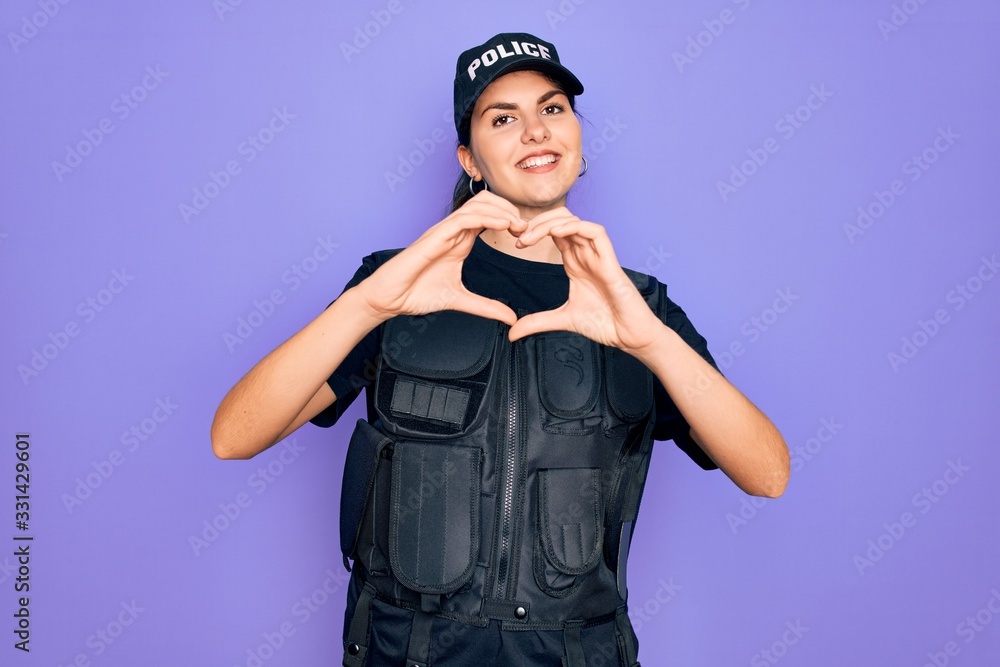 Young police woman wearing security bulletproof vest uniform over purple background smiling in love doing heart symbol shape with hands. Romantic concept. Young police woman wearing security bulletproof vest uniform over purple background smiling in love doing heart symbol shape with hands. Romantic concept.