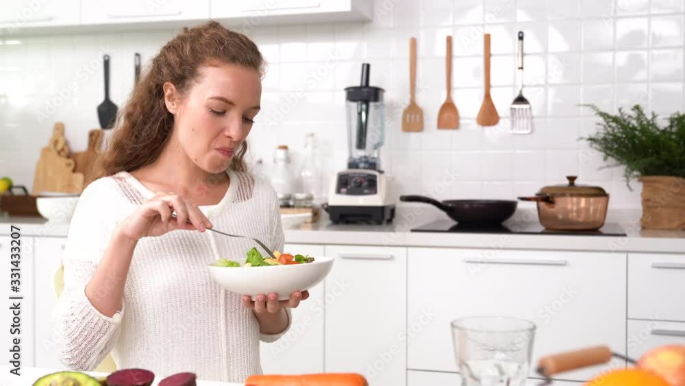 Beautiful Young woman eating salad in the kitchen . Beautiful Young woman eating salad in the kitchen .