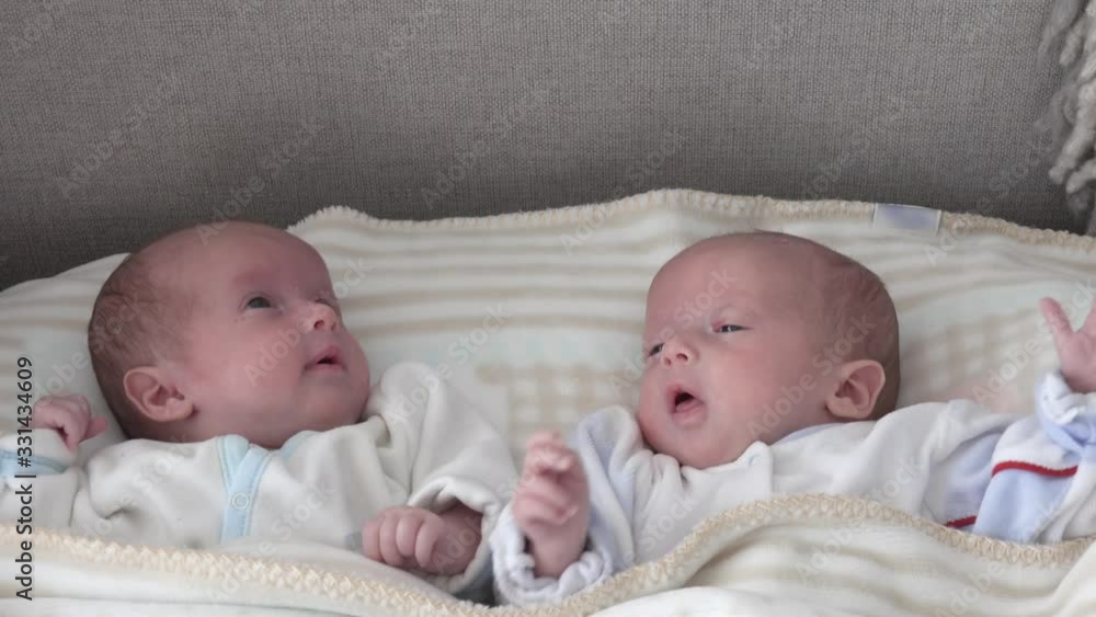 Two newborn girls sisters lie on the bed. Two baby twins on the bed Two newborn girls sisters lie on the bed. Two baby twins on the bed