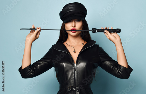 Fotografi Young beautiful sexy brunette woman in stylish black leather dress and hat stand