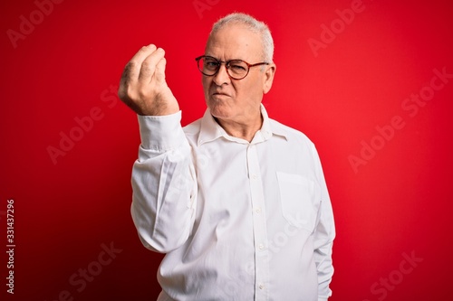 Middle age handsome hoary man wearing casual shirt and glasses over red background Doing Italian gesture with hand and fingers confident expression