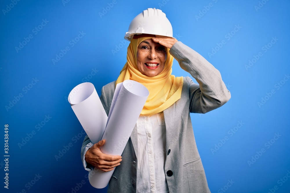Middle age architect woman wearing muslim hijab and security helmet holding blueprints stressed with hand on head, shocked with shame and surprise face, angry and frustrated. Fear and upset Middle age architect woman wearing muslim hijab and security helmet holding blueprints stressed with hand on head, shocked with shame and surprise face, angry and frustrated. Fear and upset
