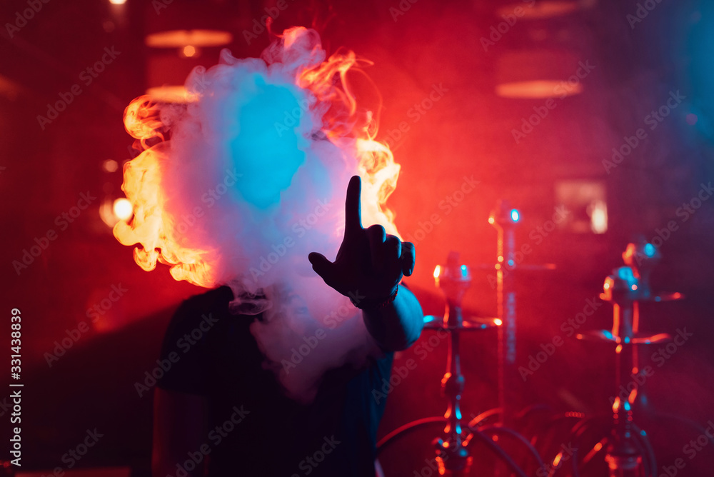 man smokes a hookah and lets out a cloud of smoke man smokes a hookah and lets out a cloud of smoke