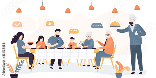Big family eats in cafe or restaurant. Handsome chef or waiter with a tray.