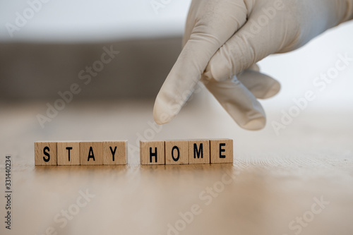 Fototapeta Konzeptbild: Hand mit Einmalhandschuh zeit auf die Worte Stay home