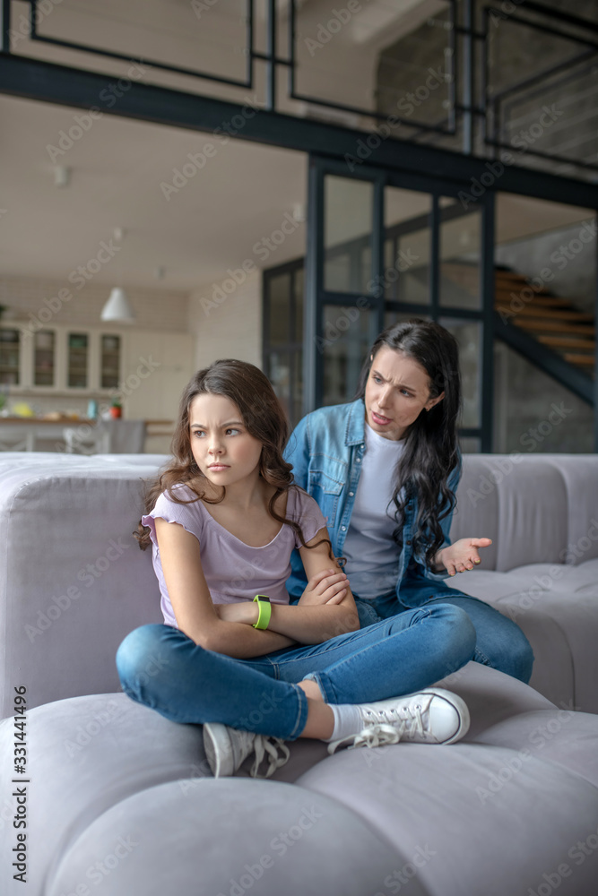 © zinkevych - Dark-haired teenager sitting next to mom in a closed pose