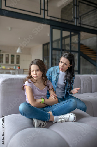 Dark-haired teenager sitting next to mom in a closed pose