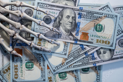 Skeleton hand holding banknotes of dollars.