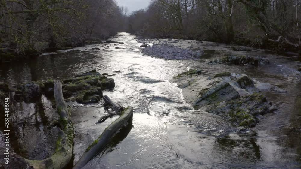 Drone shot following river through wooded valley