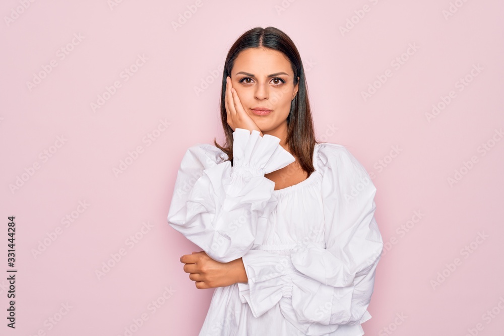 Young beautiful brunette woman wearing casual white dress standing over pink background thinking looking tired and bored with depression problems with crossed arms. Young beautiful brunette woman wearing casual white dress standing over pink background thinking looking tired and bored with depression problems with crossed arms.