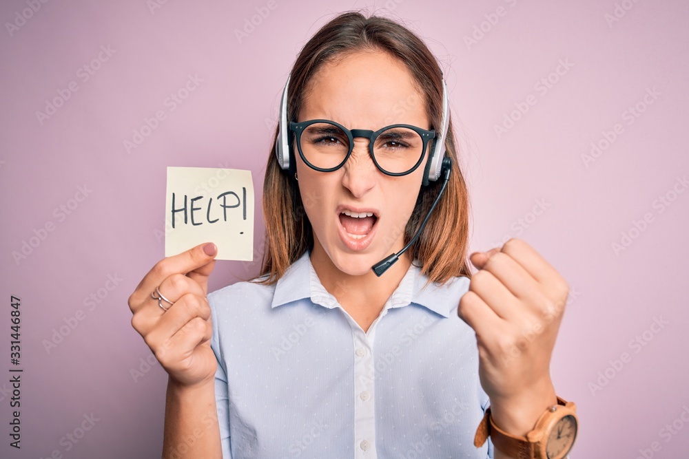 Beautiful call center agent woman working using headset holding help reminder message annoyed and frustrated shouting with anger, crazy and yelling with raised hand, anger concept