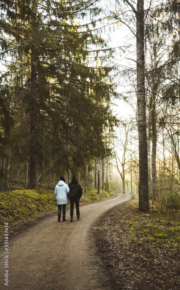 Two people walking on a curved forest road.