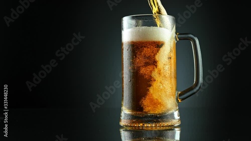 Super Slow Motion Shot of Pouring Fresh Beer into Glass on Black Background at 1000fps.