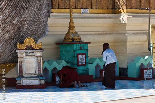 A Buddhist Monk and a female devotee praying at Old Hti of the Shwemawdaw Pagoda, Bago, Myanmar photo