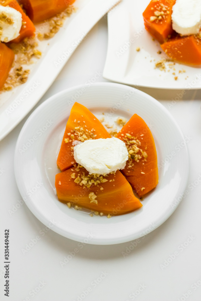 Traditional Turkish Pumpkin Dessert on the white surface.Cream and chopped walnuts topping.Vertical image Traditional Turkish Pumpkin Dessert on the white surface.Cream and chopped walnuts topping.Vertical image