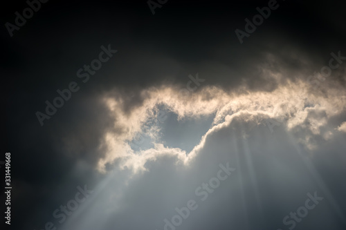An unusual cloud formation with dark storm clouds meeting light, a bright silver lining as the sun shines through a gap