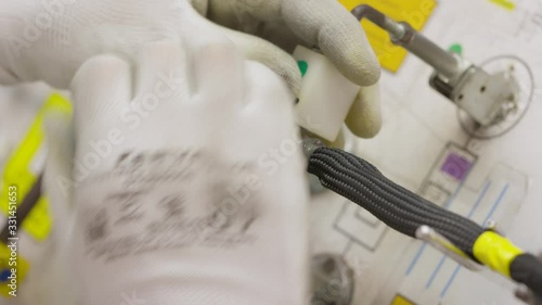 an employee winds up a wiring for cars at a modern factory in a production shop