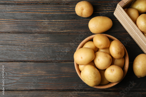 Canvas Print Bowl and basket with young potato on wooden background, top view