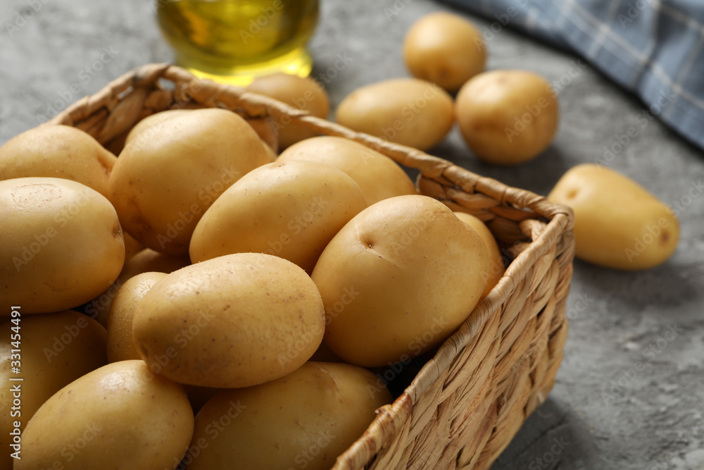 Basket with young potato on grey background, close up Basket with young potato on grey background, close up