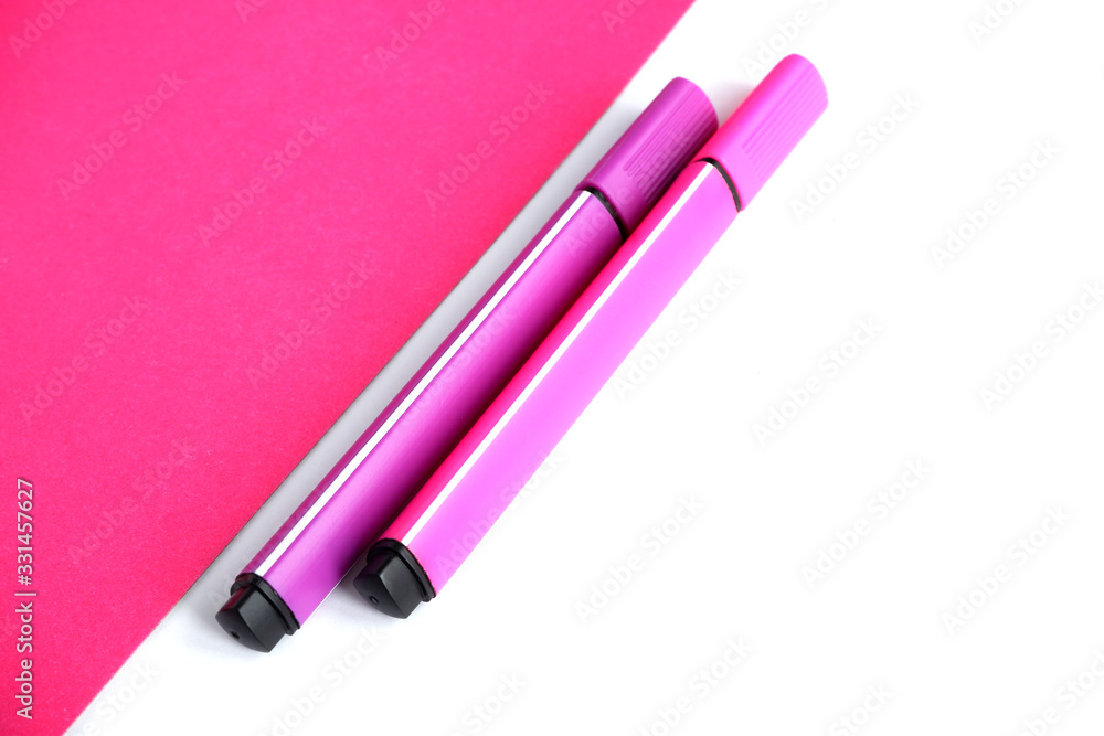 Two markers-pink and purple on a pink and white background. School supplies. Suitable for advertising background Two markers-pink and purple on a pink and white background. School supplies. Suitable for advertising background