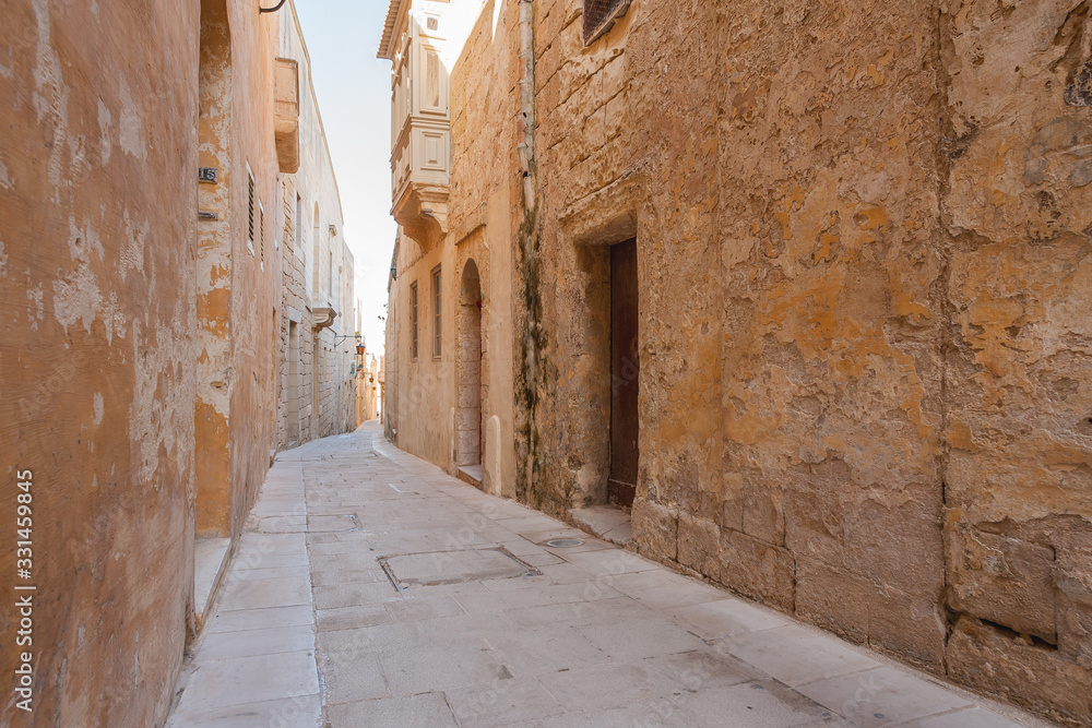 Narrow streets of Mdina, old capital of Malta. Stone buildings with old fashioned doors and balconies.