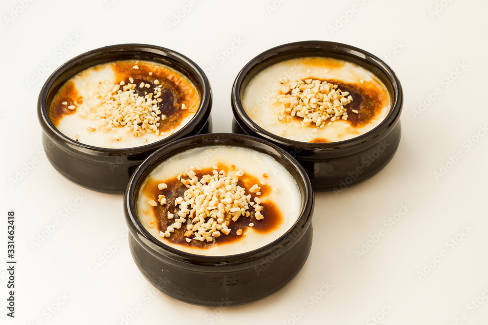 Traditional Turkish Style Baked Rice Pudding in casserole,clay dessert bowls with diced hazelnuts,on white surface.