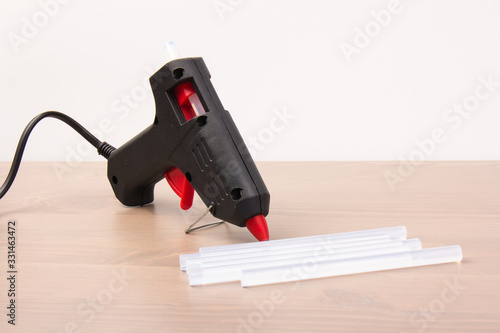 Electric hot glue gun on a wood background. Rods for glue gun