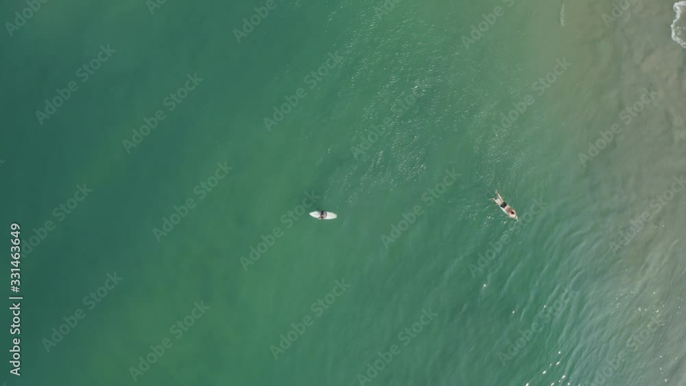 Aerial view of two men on a surfboard in the turquoise waters in Kerala, India Aerial view of two men on a surfboard in the turquoise waters in Kerala, India