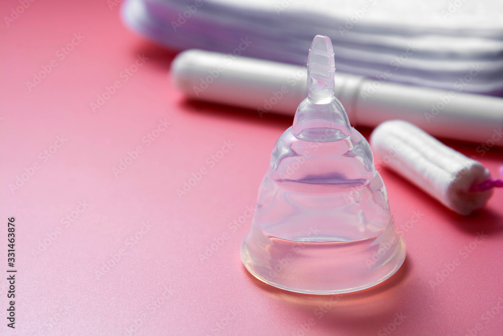 Menstrual cup and feminine hygiene tampon, isolated on pink background. Feminine hygiene products. Copy space. Menstrual cup and feminine hygiene tampon, isolated on pink background. Feminine hygiene products. Copy space.