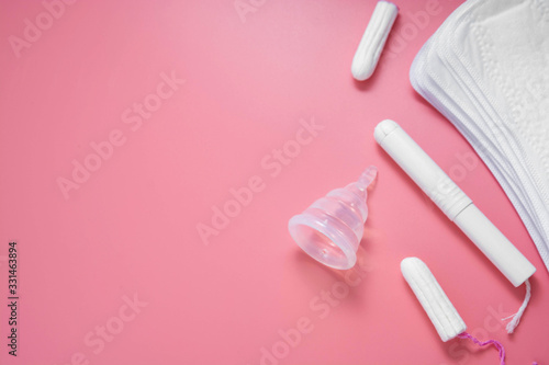 Woman hygiene products, menstruation, cotton tampons, sanitary pads, menstrual cup for woman critical days. Pink background with copy space.
