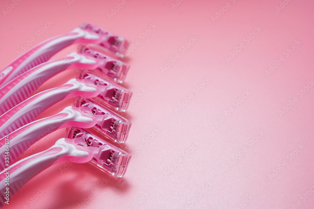 Woman pink plastic razor or stick on pink background. Disposable female shavers. Skin care.