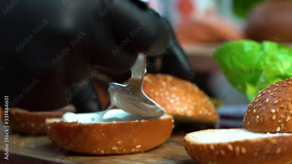 spreading mayonnaise on a bun preparing for a delicious hamburger spreading mayonnaise on a bun preparing for a delicious hamburger