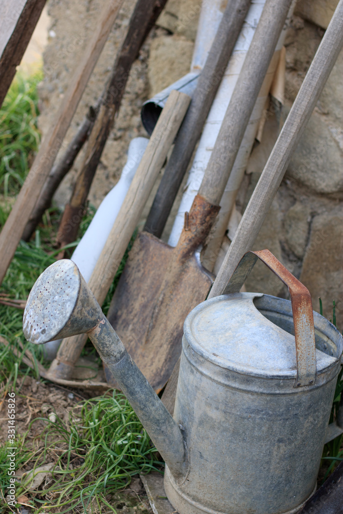 Tools for home production of vegetables and fruits, Metal watering can, shovel, rake trowel, pick - tools in the backyard. Land preparation for agriculture Tools for home production of vegetables and fruits, Metal watering can, shovel, rake trowel, pick - tools in the backyard. Land preparation for agriculture