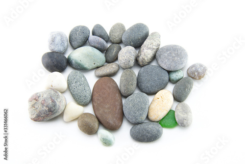 A pile of smooth multi-colored stones of small size and different colors on a white isolated background. Gray sea pebbles