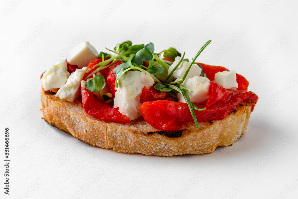 Tasty bruschetta with baked pepper, tomato and tofu. Easy cook, nutritious snack. Beautifully decorated catering banquet menu. Food snacks and appetizers for buffet. Isolated on white background.