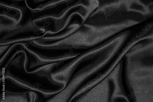 Smooth elegant black silk or satin luxury cloth texture can be used as abstract background. Crumpled fabric.