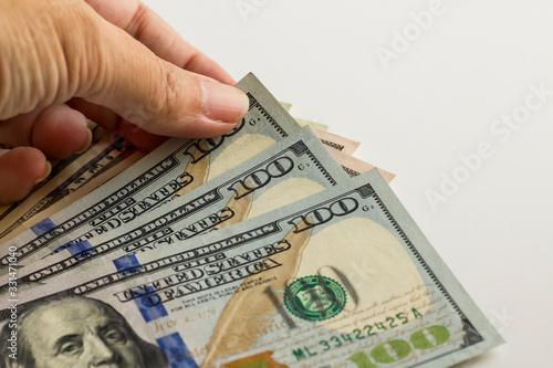 Hand selected hundred dollar in pile of American Dollars on white surface with copy space.