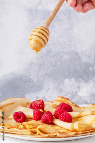 Thin pancakes withberries and honey on a plate. Breakfast concept. photo