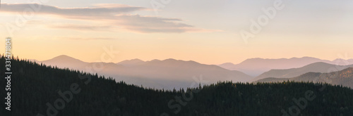 Warm gradient of dawn sky above layers of mountain and rock silhouettes. Vivid alpine landscape with dark rockies and orange sunrise sky. Minimalist highland scenery with silhouette of rocky mountains © Oleksandra