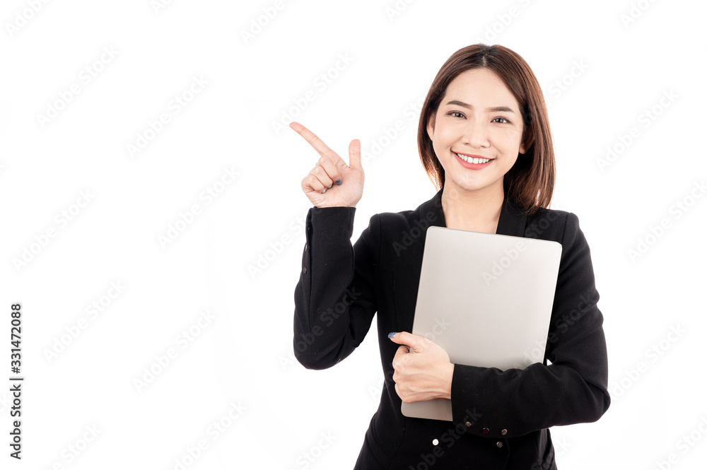 Asian businesswoman with black suit holding a laptop and pointing to present copy space with big smile beaming face in white isolated background. Asian businesswoman with black suit holding a laptop and pointing to present copy space with big smile beaming face in white isolated background.