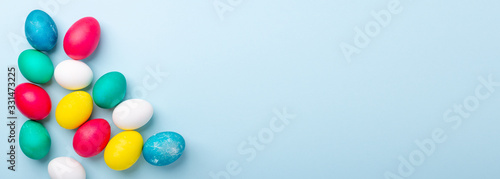 Easter composition. Multicolored easter eggs on blue background. Copy space. Horizontal banner © lizaelesina