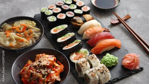 Composition of different kinds of sushi rolls placed on black stone board