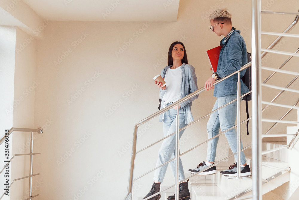 Two young student friends together on the stairs in college