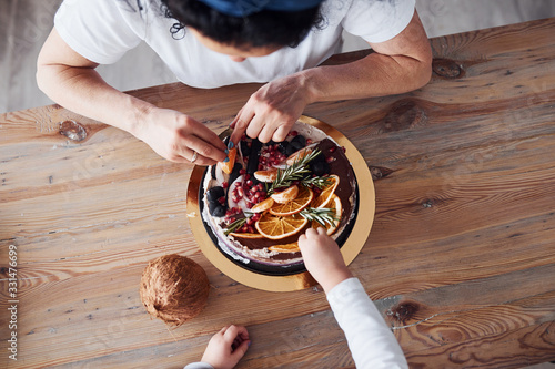 Top view of woman with her granddaughter preparing dietical cake on kitchen photo