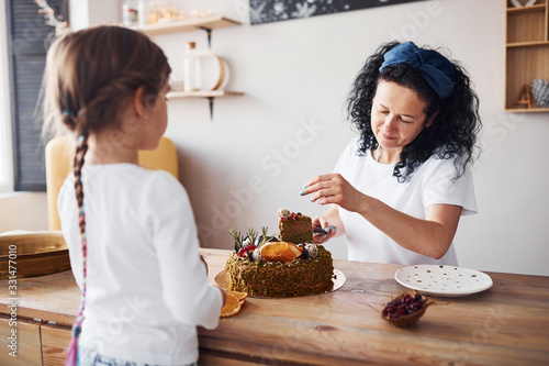 Senior woman with her granddaughter eating fresh dietical cake on kitchen
