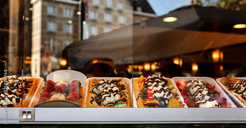 Fototapeta premium Assorted mouth-watering Belgian waffles in a shop window. Panorama format.