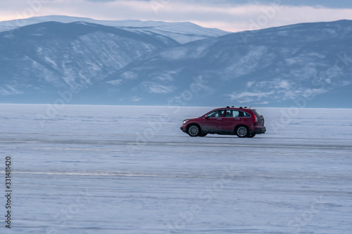 Travel by car on the ice road of the frozen lake Baikal in Siberia. Only ice, snow, and mountains