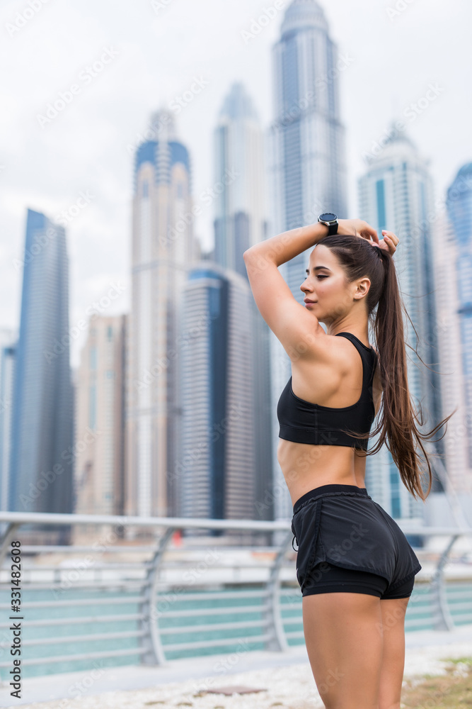 Fitness woman runner relaxing after city running and working out outdoors. The girl straightens her hair, tying her hair in a ponytail.